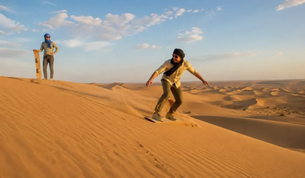 Traveler sandboarding on the golden Erg Chebbi dunes near Merzouga, Morocco